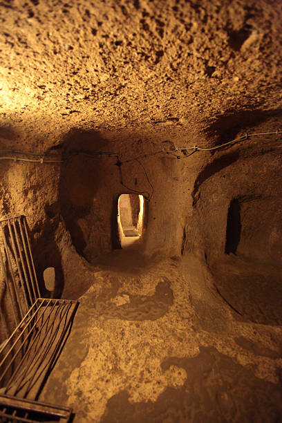 Kaymaklı Underground City is contained within the citadel of Kaymaklı in the Central Anatolia Region of Turkey. First opened to tourists in 1964, the village is about 19km from Nevşehir, on the Nevşehir-Niğde road. The ancient name was Enegup. The houses in the village are constructed around the nearly one hundred tunnels of the underground city. The tunnels are still used today as storage areas, stables, and cellars. The underground city at Kaymaklı differs from Derinkuyu in terms of its structure and layout. The tunnels are lower, narrower, and more steeply inclined. Of the four floors open to tourists, each space is organized around ventilation shafts. This makes the design of each room or open space dependent on the availability of ventilation.