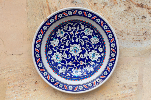 A closeup of a vintage white plate with blue floral ornaments on a gray surface