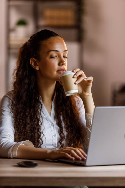 istock Young woman using laptop at office, drinking coffee 1640121918