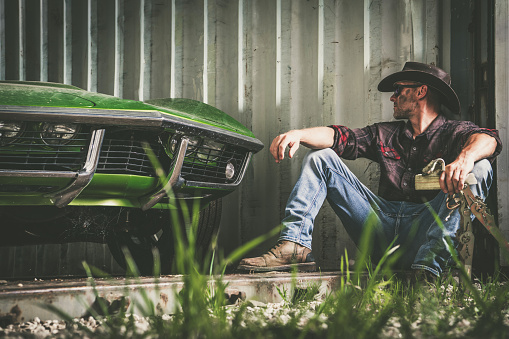 Caucasian American Cowboy Seating Next to His Storage with His Classic Car
