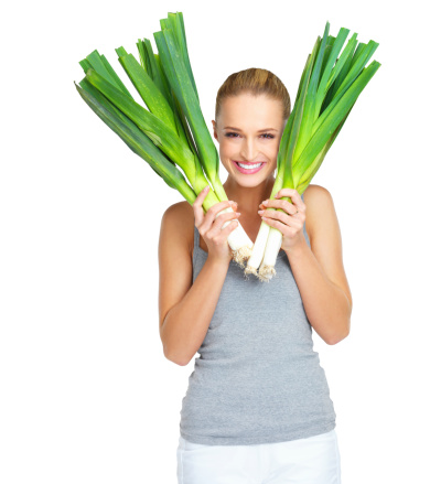 Pretty young woman holding up some leeks with a smile