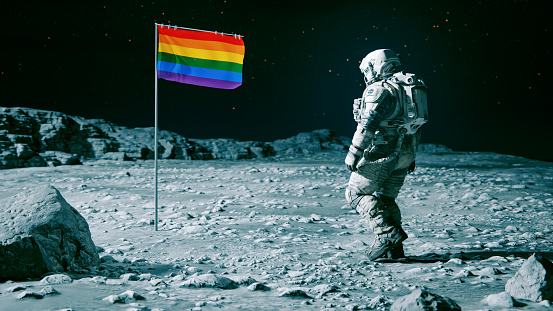 Astronaut on a space mission encounters a flag with rainbow colors on another planet or a moon.