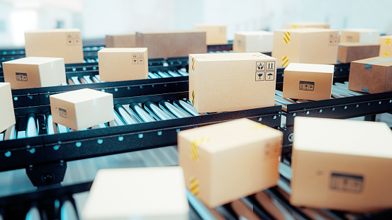 Inside a warehouse stands lots of conveyor belts. Cardboard boxes and packages rolls through the factory. Concept of logistic and efficiency.