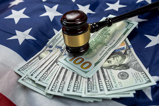 judge's gavel of justice is placed together with dollars on the background of the flag of the United States of America. symbol of jurisdiction. Bribes in the country's justice system