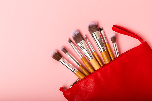 Cosmetic makeup brush on a pink background. Cosmetic product for make-up. Creative and beauty fashion concept. Fashion. Collection of cosmetic makeup brushes, top view, banner.Place for text.