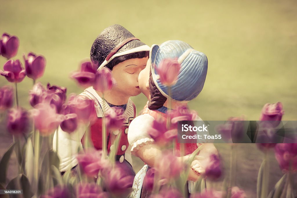 Two kissing vintage dolls in tulip garden. Boyfriend Stock Photo