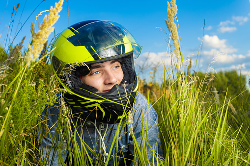 Man in helmet between tall grass under a beautiful landscape sky