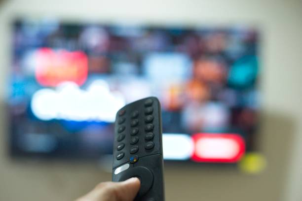 istock Hand with TV remote control, switching TV series from streaming service platform. The new way of enjoying entertainment at home. 1640212713