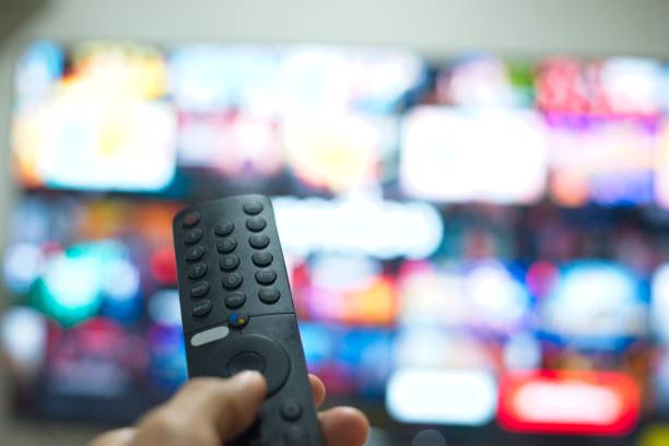 istock Hand with TV remote control, switching TV series from streaming service platform. The new way of enjoying entertainment at home. 1640212716
