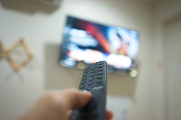 istock Hand with TV remote control, switching TV series from streaming service platform. The new way of enjoying entertainment at home. 1640213246
