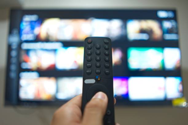 istock Hand with TV remote control, switching TV series from streaming service platform. The new way of enjoying entertainment at home. 1640213267