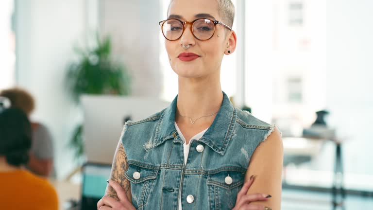 Face, creative designer and woman with arms crossed in office, startup company and workplace for job. Portrait, glasses and professional entrepreneur, producer and confident employee worker coworking