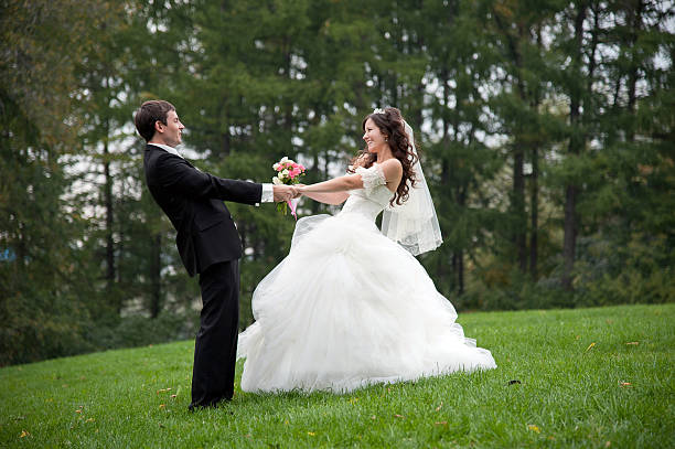 Newly married couple dancing in field. Outdoor portrait of bride and groom