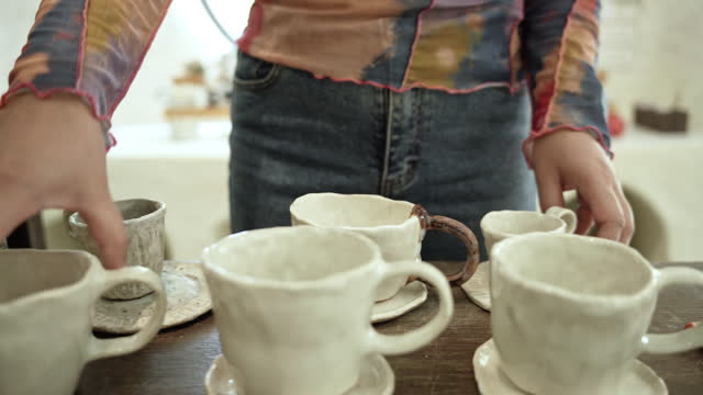 Woman hand holding ceramic by hand made in in a ceramics studio Hand-made ceramic mug by artist.