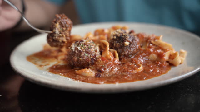 Man eating spaghetti and beef Meatballs with tomato sauce in Italian restaurant