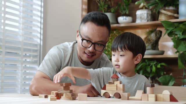 Asian fathers and sons playing with building blocks in the living room