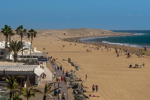 Beach with boulevard and restaurants and the famous and protected sand dunes of Maspalomas, Gran Canaria, Spain.