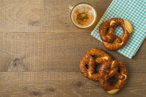 Beer Fest party concept with pretzel and beer glass over wooden background. Top view, flat lay