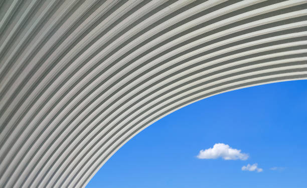 grande telhado de cúpula de aço ondulado curvo contra 2 mini nuvens no fundo do céu azul em estilo mínimo, visão de baixo ângulo com espaço de cópia - architecture roof aluminum sheet industry - fotografias e filmes do acervo