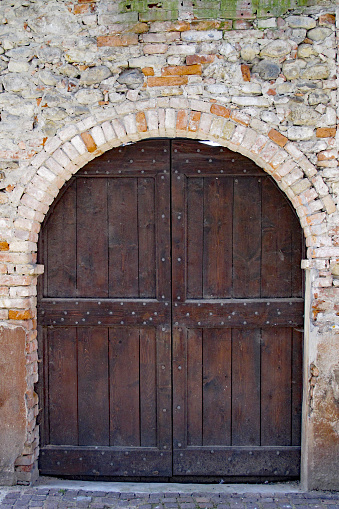 Barolo, Italy 04-10-2011 Rustic wood door in brick arch in Barolo, in Piemonte wine region of northern Italy.
