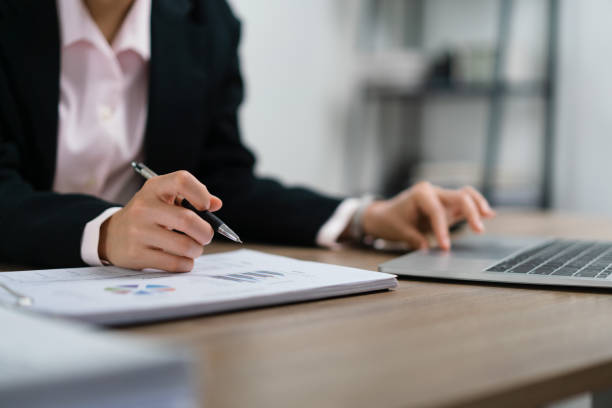 istock Businesswoman writing notes on document and typing data on laptop about marketing plan of startup 1640337189