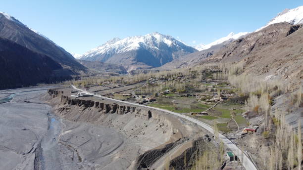 A village at Pak-China border (Serteez-Gircha in Hunza valley) Picture taken toward the Pak-China and Pak Afghan border near Sost, last town of Hunza valley of Pakistan Border. The grey line shows Karakorum High Way leading toward China, built by the People of Pakistan and China as a symbol of friendship. At the right side are the whitish color showing tall Poplar and willow trees famous in Pakistan. karakoram highway stock pictures, royalty-free photos & images