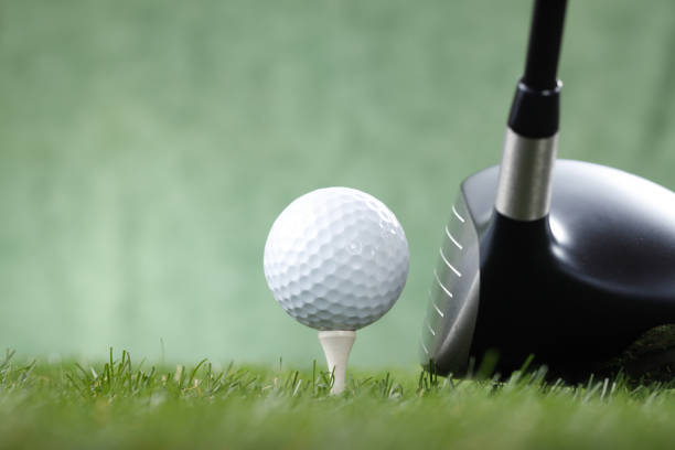A blue glow lights a golf ball sitting on a glowing green tee with driver about to strike.