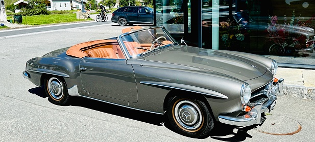 Sils-Maria, Switzerland - August, 22nd - 2030: Golden metallic Mercedes Benz Oldtimer convertible 190 SL parked on a street.