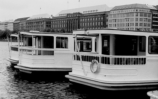 Stern view of the tourist boats on the Alster. In the background are the office buildings of a large German shipping company and a luxury hotel.