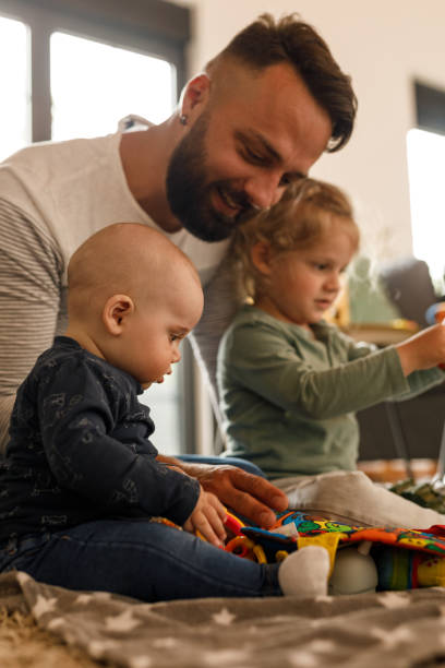 istock Man sitting on the floor, playing with his two little sons 1640372368