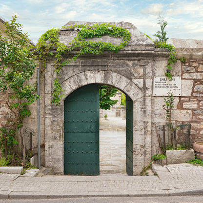 Arched entrance with green metal door in brick stone wall leading to 17th century Cinili Mosque in Uskudar, Istanbul, Turkey