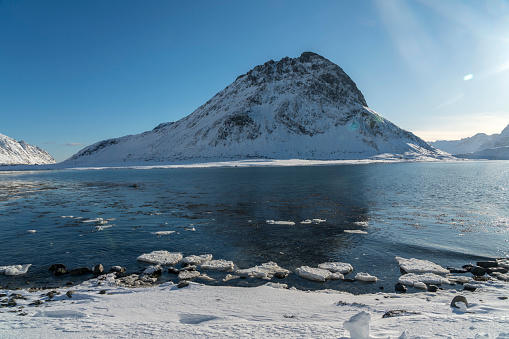 Winter landscape of Torsfjorden fjord on island of Moskenesøya in the Lofoten archipelago in Nordland county in winter. Frozen sea slowly melting.