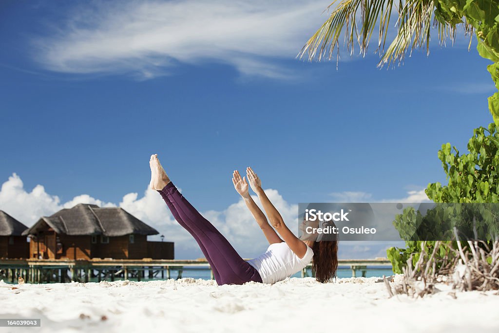Bella donna facendo esercizi di yoga sulla spiaggia tropicale - Foto stock royalty-free di Adulto