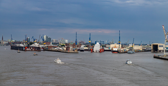 Hamburg, Germany - July 15, 2023: View from the water to the docks for yacht maintenance. In the background the city of Hamburg and the Elbphilharmonie, which will open on January 11, 2017.