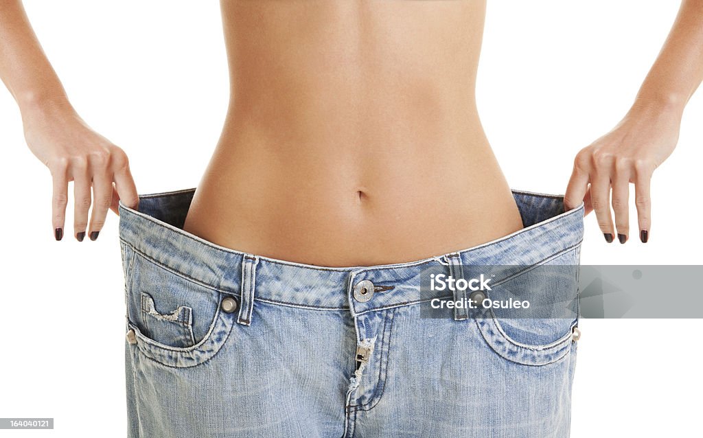 woman shows her weight loss by wearing an old jeans woman shows her weight loss by wearing an old jeans, isolated on white background Abdomen Stock Photo