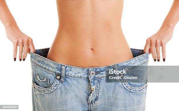 Woman Shows Her Weight Loss By Wearing An Old Jeans Stock Photo - Download Image Now