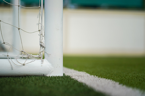 A football goal post structure which is placed on artificial turf ground pitch. Sport equipment object photo.