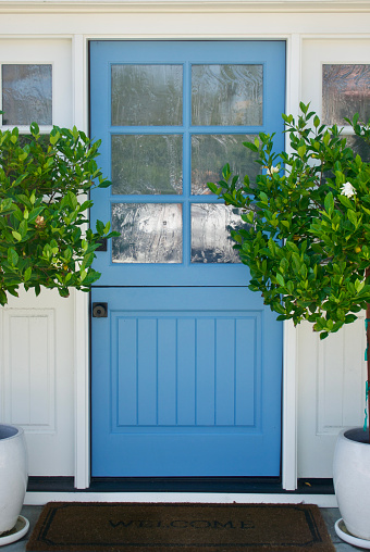 Cottage with bright blue front door and gardenia topiaries