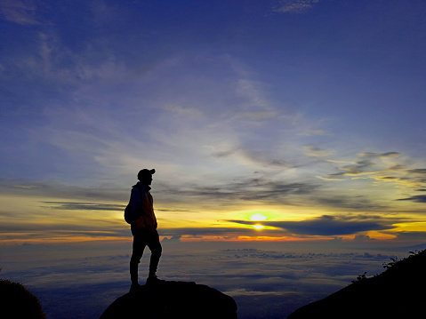 mountain climbers who see the sun rising above the clouds, with a bright light
