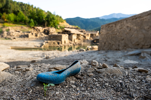 An old-fashioned plastic child's shoe in an abandoned village.
