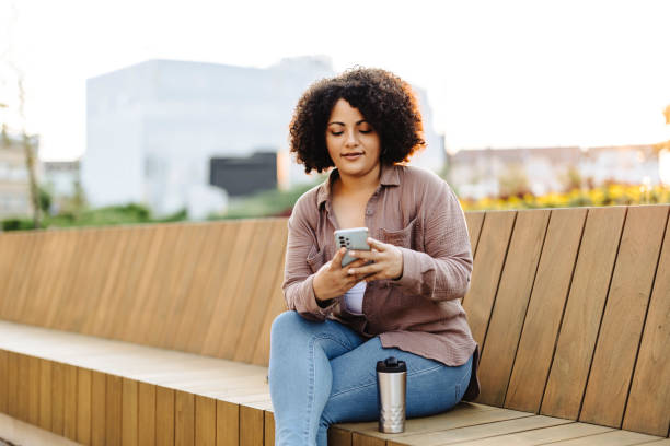 istock Young female student using her smart phone and sitting on bench 1640502264