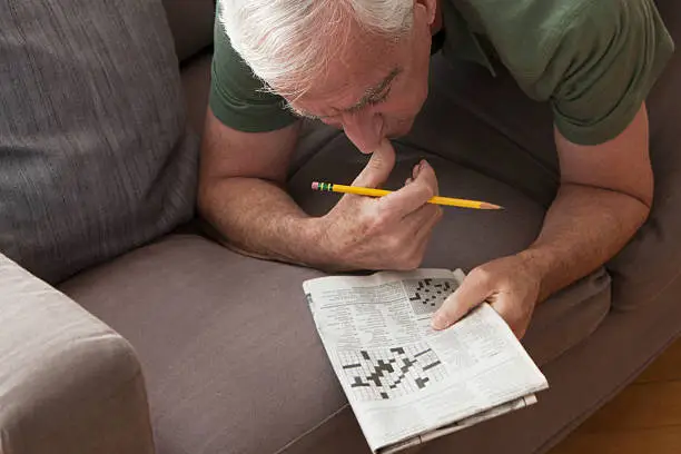 Caucasian senior man working on crossword puzzle, horizontal view