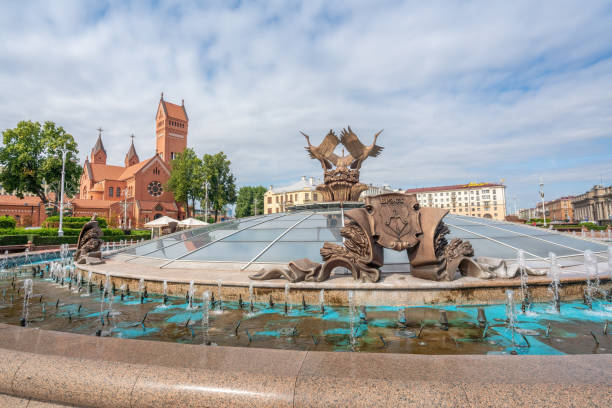 Fountain of Three Storks at Independence Square and Church of Saints Simon and Helena - Minsk Red Church - Minsk, Belarus stock photo