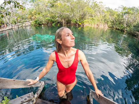 She wears a red swimsuit against the deep blue color of the water,\nQuintana Roo, Mexico.