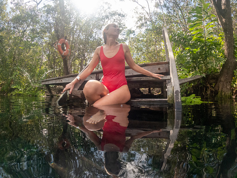 She wears a red swimsuit against the deep blue color of the water,
Quintana Roo, Mexico.