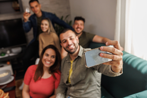 Portrait of joyful group of friends taking selfies together while hanging out.