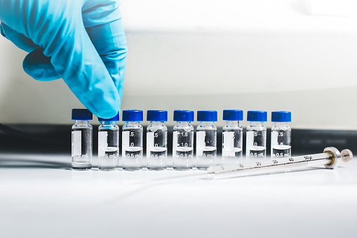 Hand of the scientist pick up the vial of sample solution to analyze by Liquid Chromatography mass spectrometry LC-MS instrument in the laboratory. The LC-MS is used for scientific research.