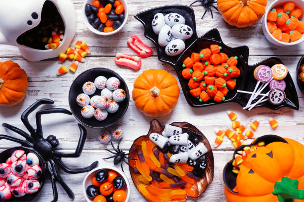 istock Halloween trick or treat candy table scene, above view on white wood 1640585032