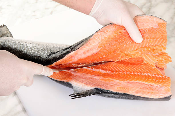 Chef's hands cutting a fresh salmon
