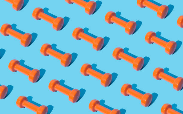 istock Creative pattern composition made of orange dumbbells on light blue background. Minimal fitness, healthy lifestyle and sport concept. Trendy exercise and fitness backround idea. 1640614512